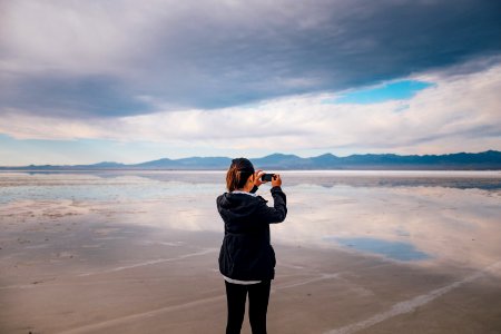 woman in gray jacket standing on beach during daytime photo