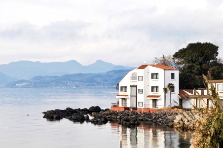 white and brown house at lakeside under grey cloudy sky photo