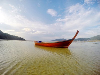 A red boat sitting in water near the shore. photo