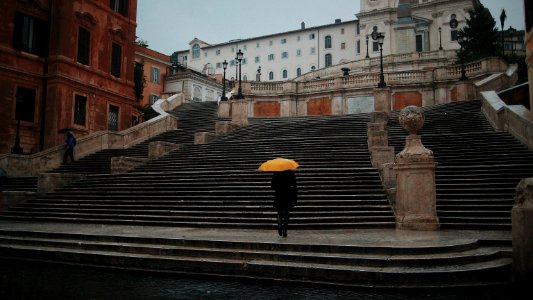person holding yellow umbrella standing on concrete stairs photo