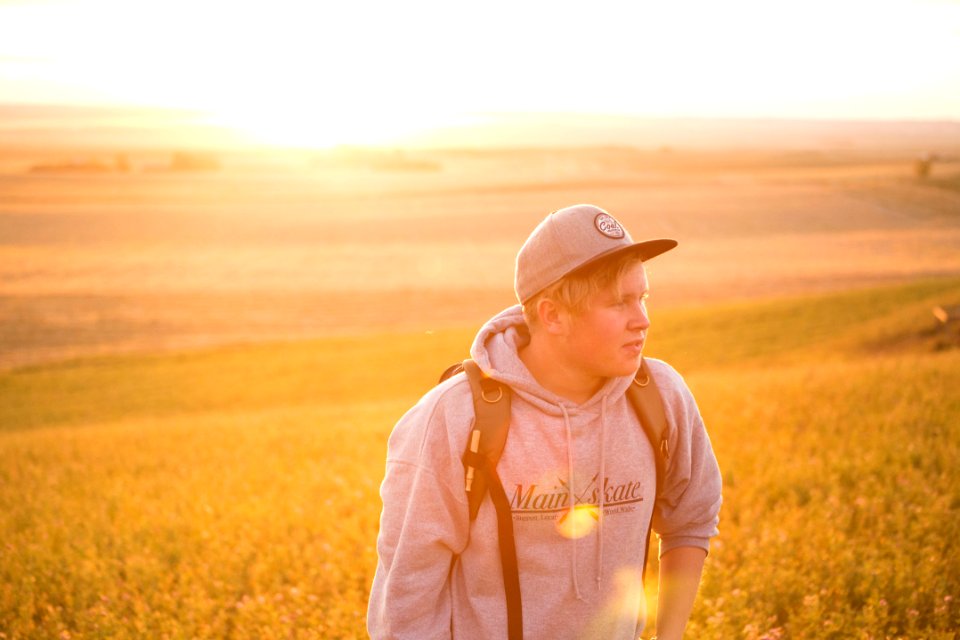 man wearing gray pullover hoodie near green grass at daytime