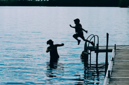 photography of boy jumping on body of water during daytime photo