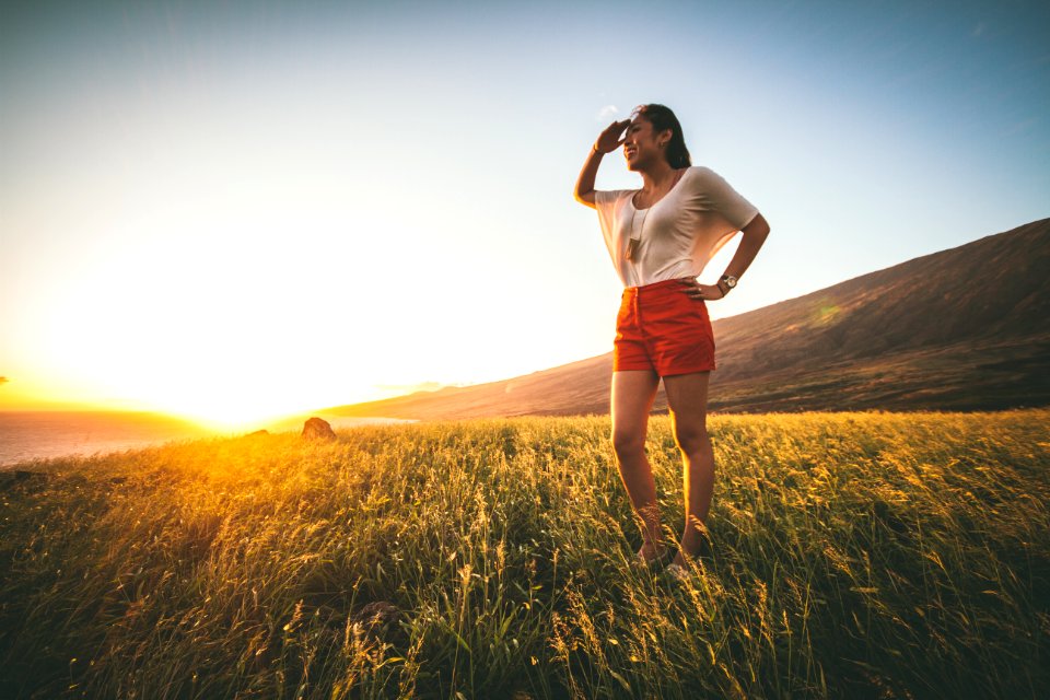 woman in beige batwing sleeved shirt and red shorts standing on grass field