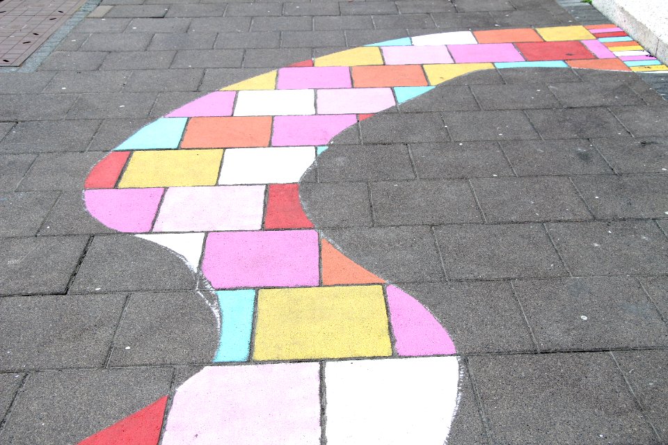 A curvy section of bricks painted with various light colors.