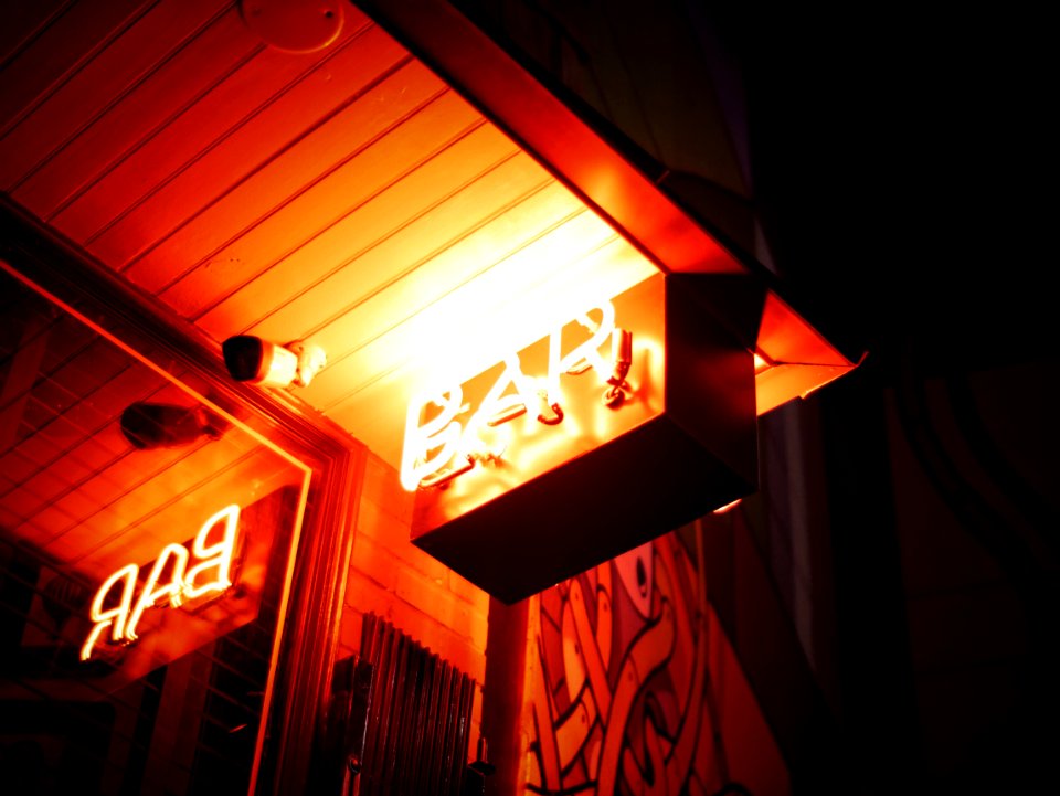 orange Bar signage beside bullet security camera