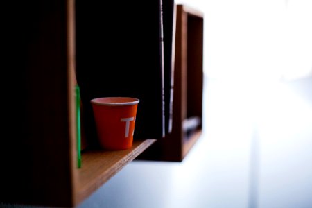 red disposable cup on brown wooden shelf