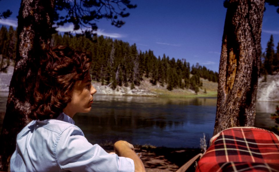 boy sitting near on lake under blue sky