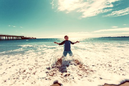 boy playing on shore under blue sky during daytime photo