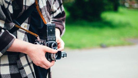person carrying DSLR camera in shallow focus photography photo