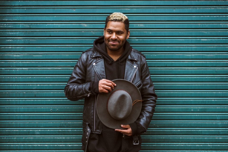 man holding black cowboy hat standing in front of roll-up door