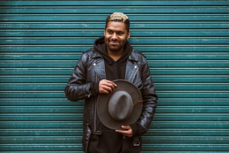 man holding black cowboy hat standing in front of roll-up door photo