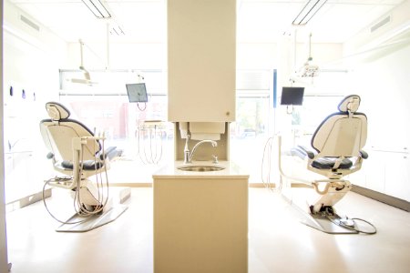 two white dentist chairs inside white painted room photo