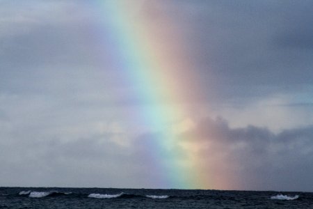 A rainbow shining through a cloudy sky. photo