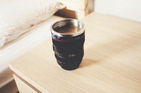 black DSLR camera lens travel mug on nightstand photo