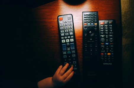 three black remote controls on wooden table photo