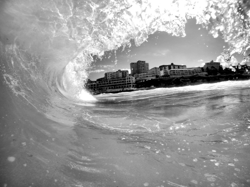 A gray image taken inside of a wave as it splashes overhead. photo