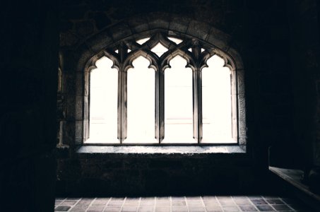 A darkened picture capturing a window inside of a church. photo