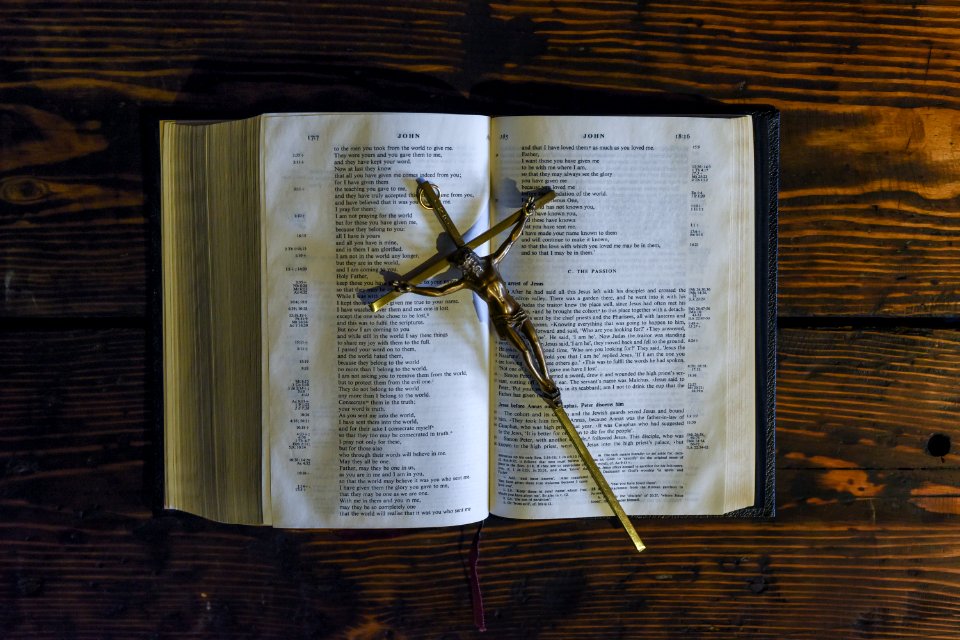 A cross with Jesus on it sitting on top of an open bible. photo