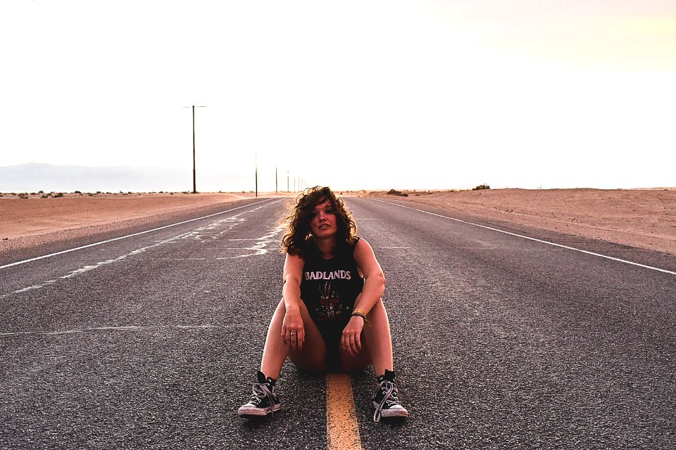 A rocker chick sitting on the yellow line in the middle of a road.