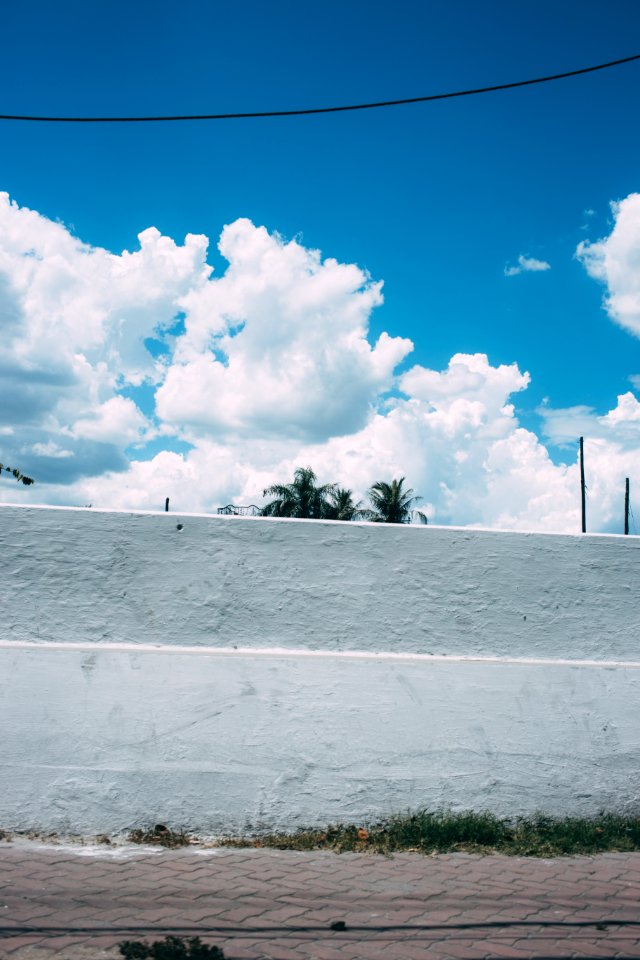 white concrete wall under white clouds and blue sky during daytime