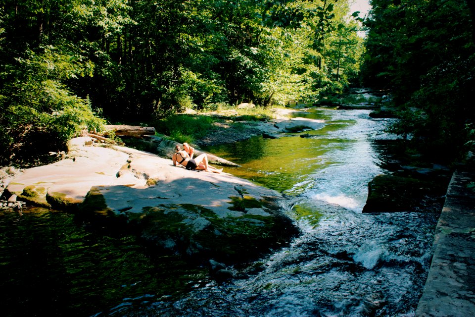 two women sitting on rock beside river