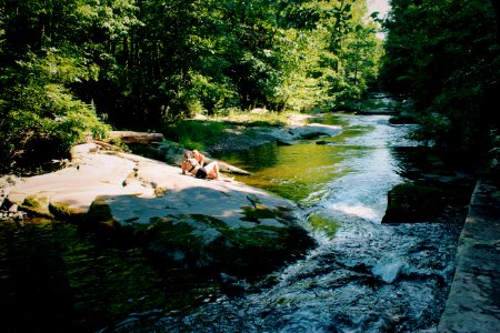 two women sitting on rock beside river