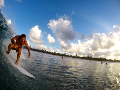 A person surfing on a small wave at a busy beach. photo