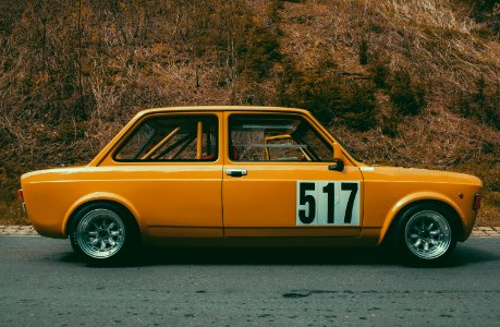 classic yellow and white sedan parked beside green plant photo