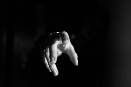 A persons hand reaching for the camera, surrounded by darkness. photo