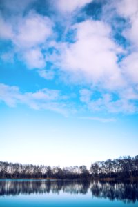 calm body of water by treeline under blue skies photo