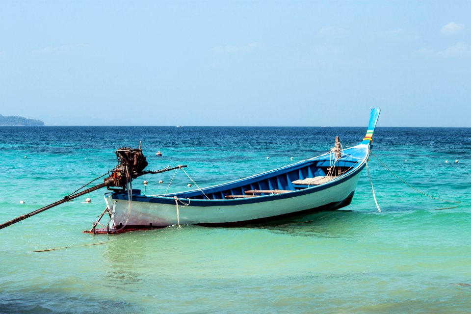 man in brown shirt riding on blue and white boat during daytime photo