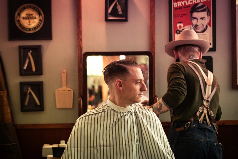 man sitting on chair inside barber shop