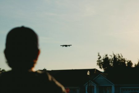 man standing while watching plane on sky during daytime photo