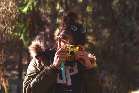 woman in black jacket holding green and white camera photo