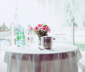 pink petaled flower centerpiece on white table beside container photo