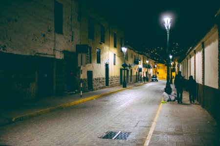 man in black jacket walking on sidewalk during night time photo