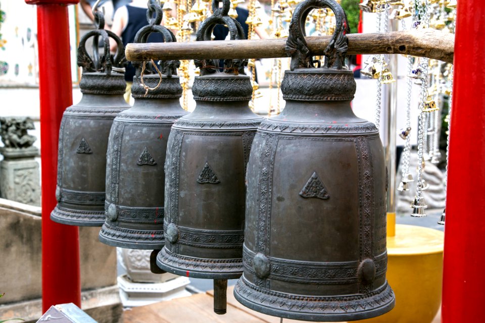 black metal bell on brown wooden fence