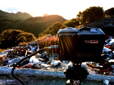 A GoPro camera set up on a tripod in a mountain area. photo