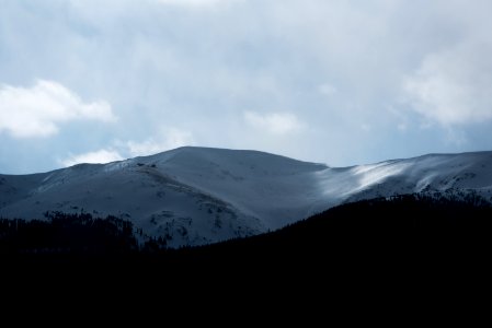 A mountain covered in snow near clouds photo