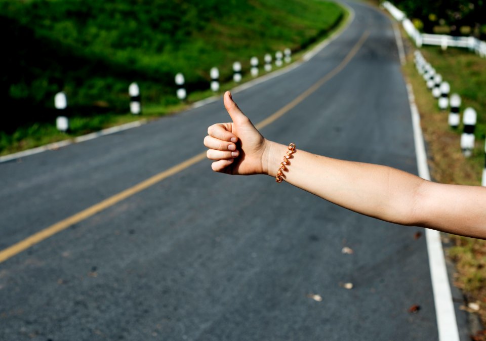 Hitch hiking sign near road 