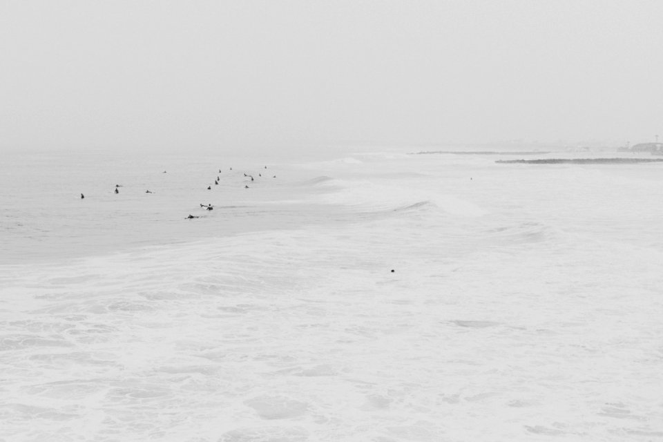 Surfers under the white sky 