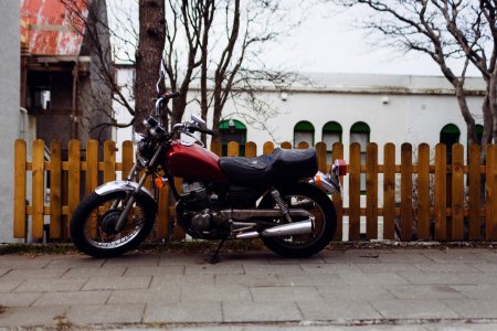 Black and Maroon Motorcycle Parked Beside Brown Wooden Fence