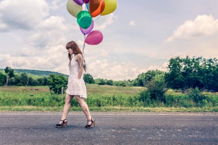 Photography of Woman Walking Near Road Holding Balloons photo