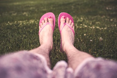 Selective Focus Photography of Person Sitting While Wearing Pair of Pink Flip-flops