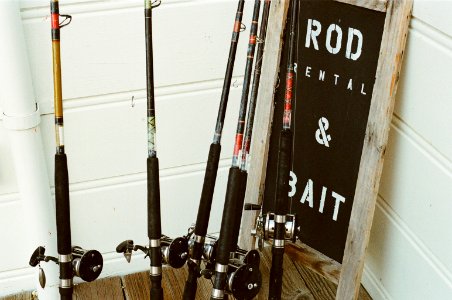 Six Assorted Fishing Rods Beside Rod Rental & Bait Signage