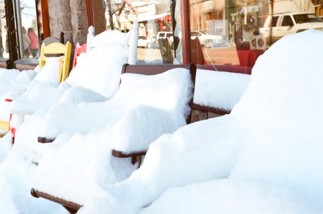 Snow Coated Chairs Beside Clear Glass Storefront photo