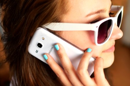 Smiling Woman Wearing Sunglasses While Talking on White Samsung Smartphone photo