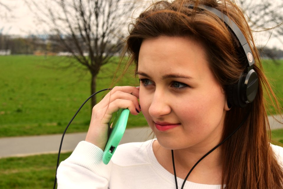Smiling Woman Wearing Black Headphones Near Black Bare Tree