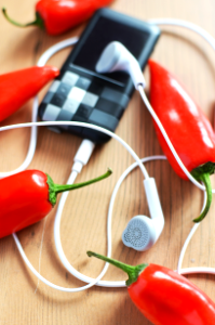 White Earphones Connected to Mp3 Player Surrounded by Red Chili Peppers photo