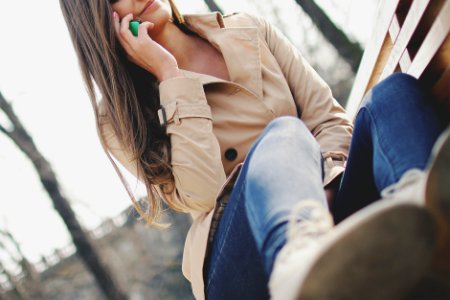 Woman Holding Smartphone While Sitting on Bench photo